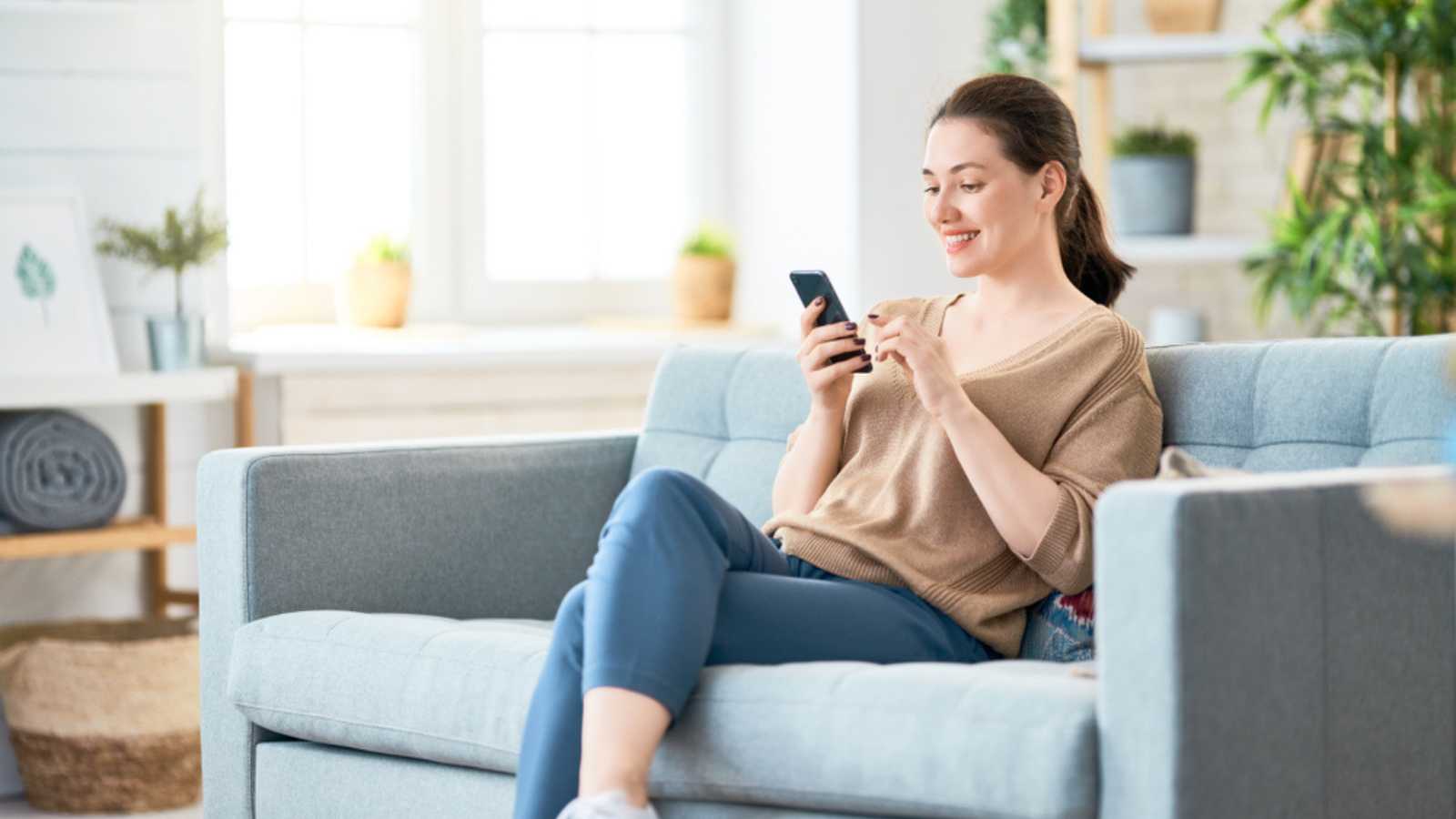 Woman Looking At Mobile In Sofa