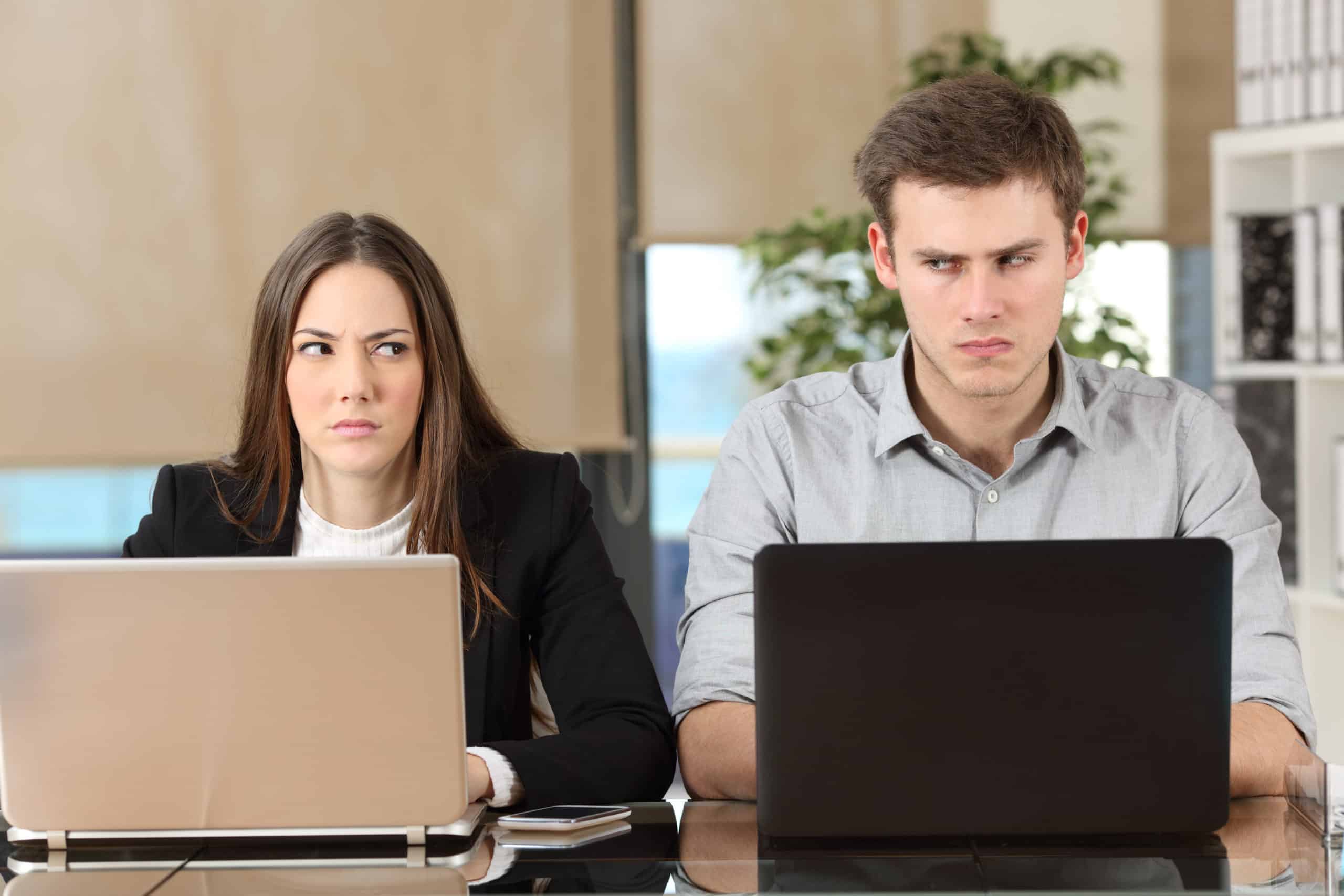 Front View Of Two Angry Businesspeople Using Computers Disputing At