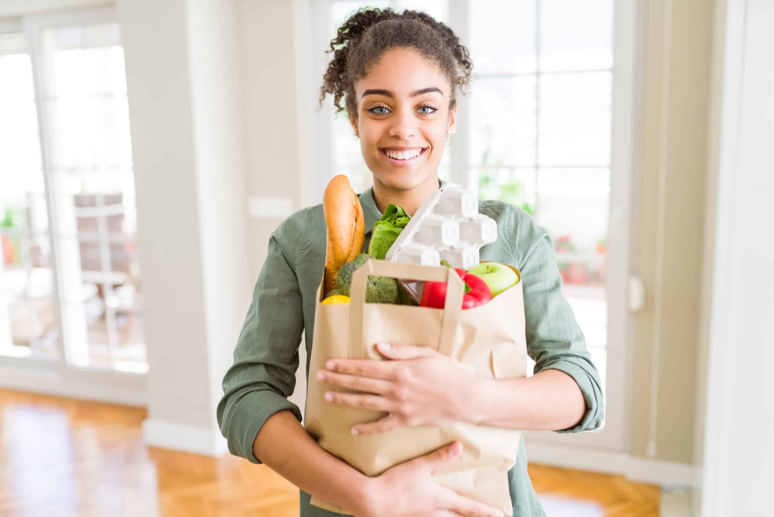 Young African American Girl Holding Paper Bag Of Groceries From